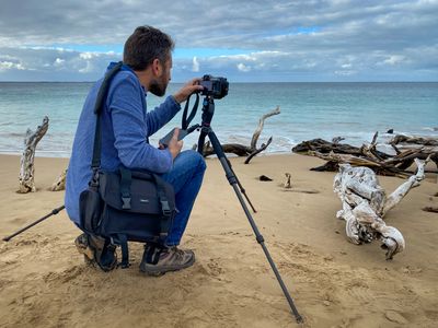 Clancy setting up a tripod on a quiet beach.